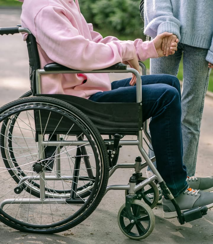 Persona en silla de ruedas recibiendo asistencia en un parque