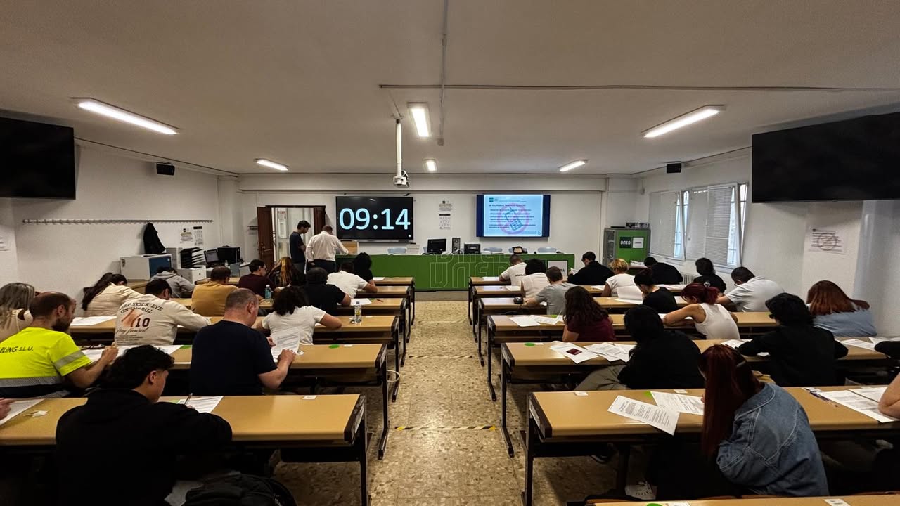 Estudiantes realizando exámenes en UNED Zamora con un reloj visible