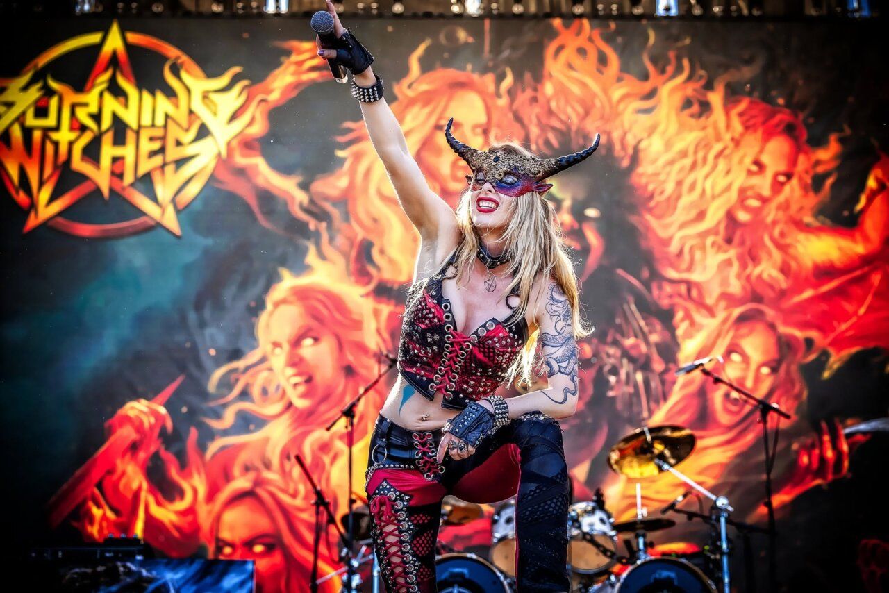 Cantante de Burning Witches en concierto con fondo de llamas