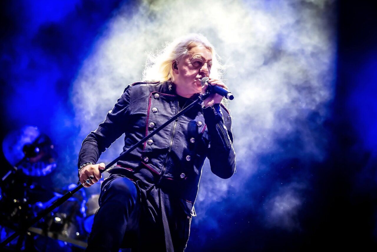 Vocalista de banda de metal en concierto con luces azules de fondo
