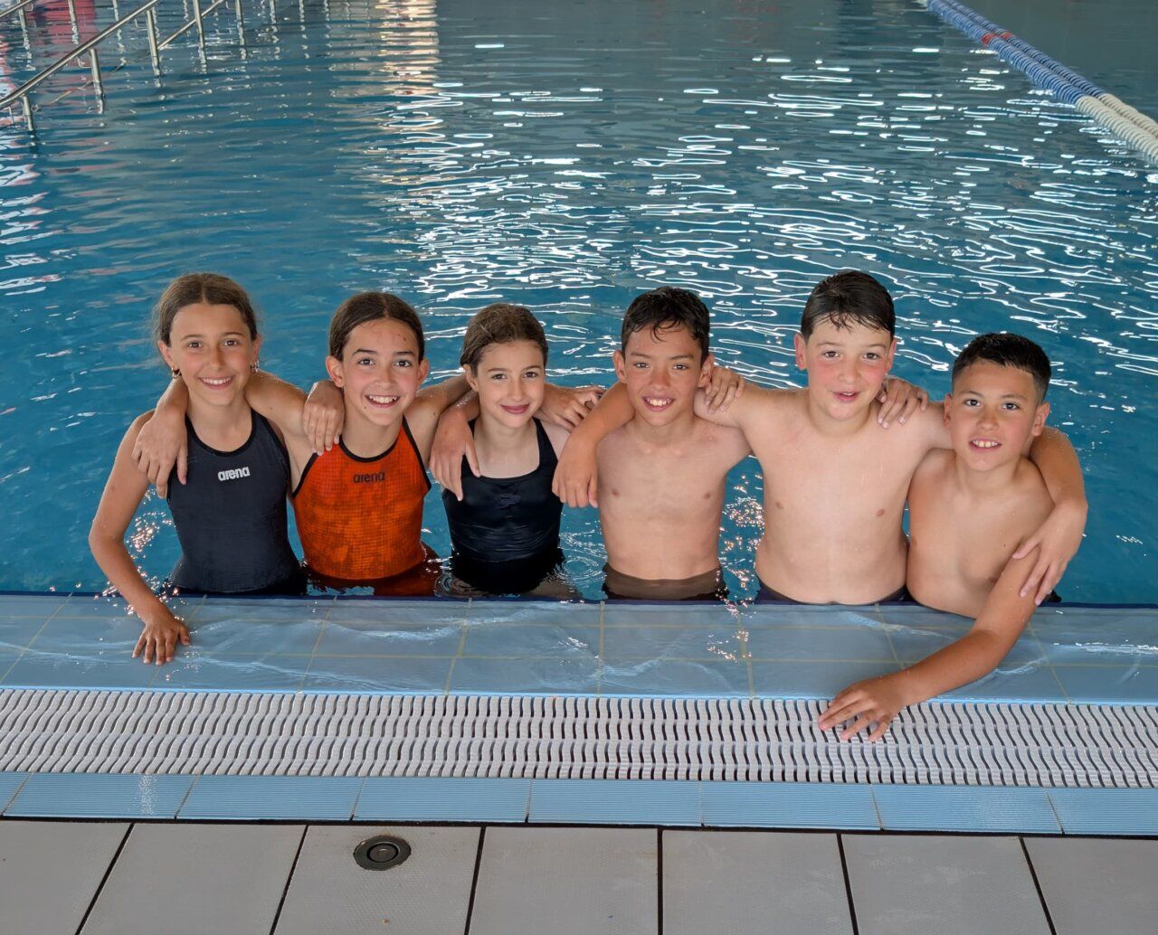 Grupo de niños sonrientes en la piscina tras una competición de natación
