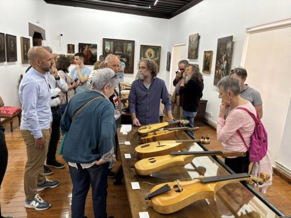 Personas observando instrumentos de cuerda en una exposición de violas medievales.