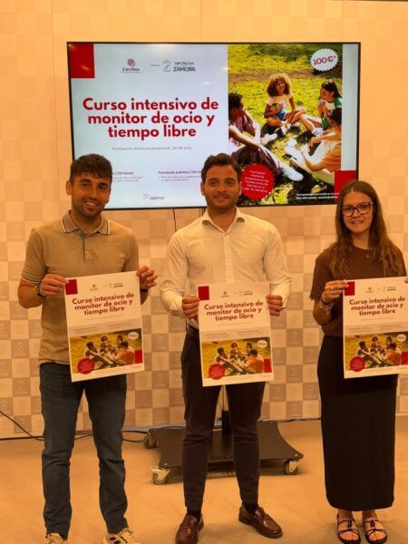 Presentación del curso de monitor de ocio y tiempo libre en Zamora con tres personas sosteniendo carteles.