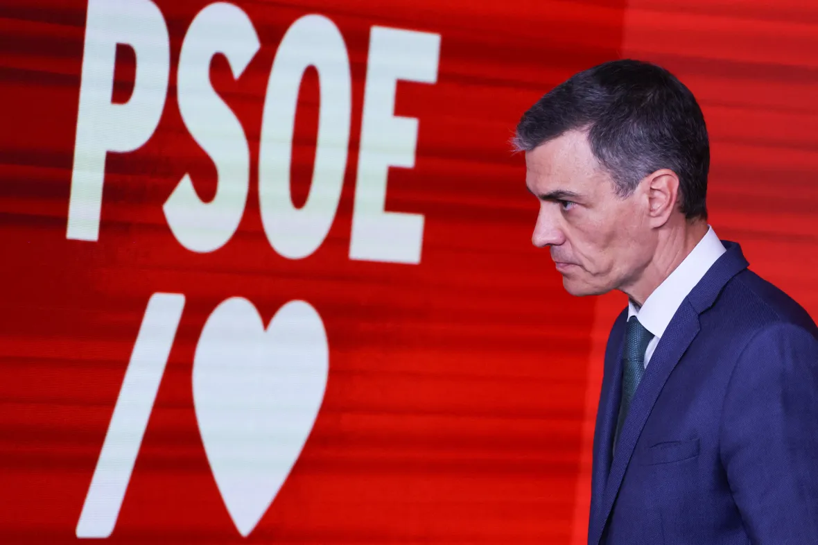 Pedro Sánchez caminando frente a un fondo con el logo del PSOE