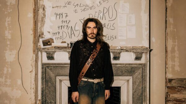 Carlos Ares posando en un ambiente artístico con fondo decorado