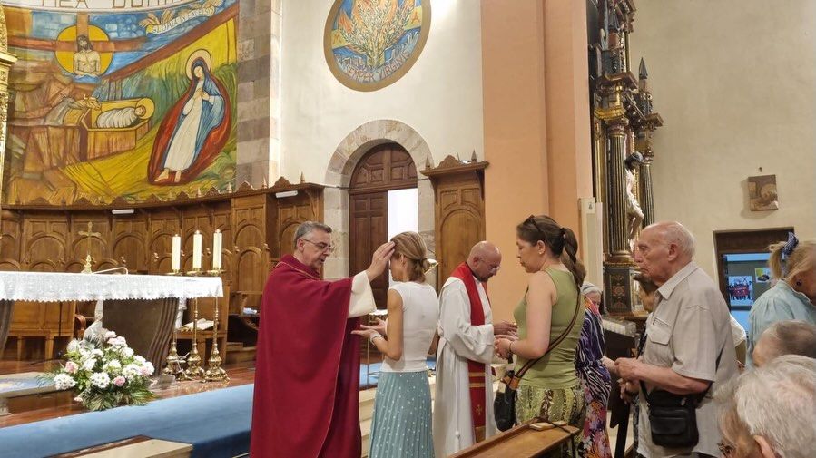 Sacerdote ungiendo a fieles en la Parroquia de Lourdes