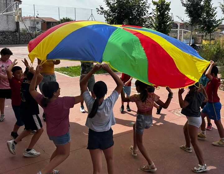 Niños jugando con un paracaídas colorido en el centro de apoyo