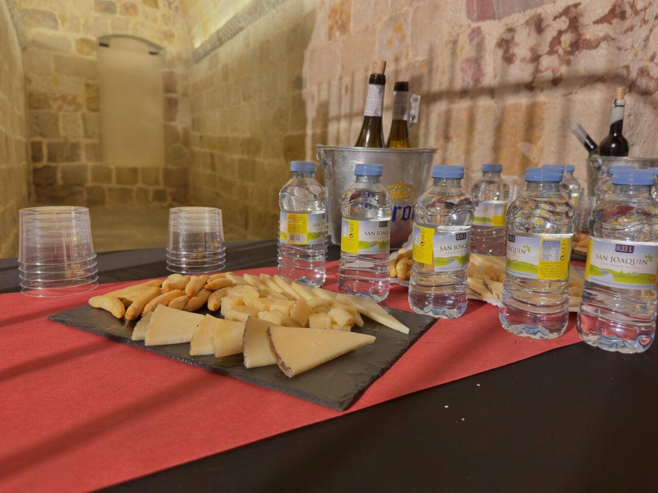 Mesa con degustación de quesos y botellas de agua en un entorno histórico