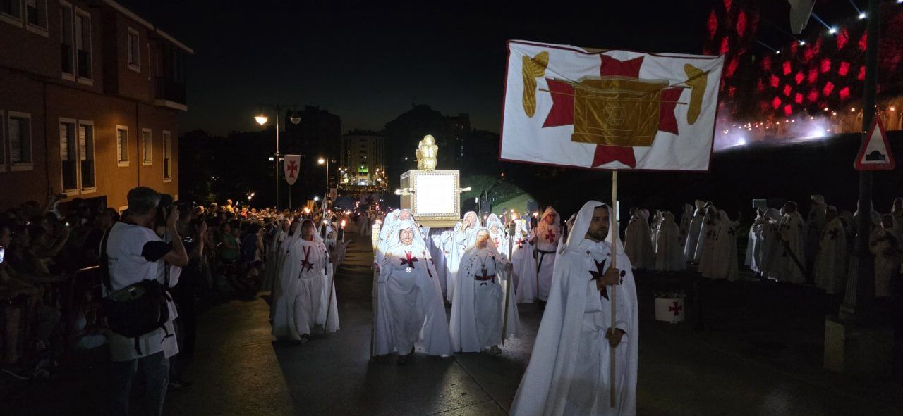 Participantes en el desfile templario de Ponferrada con vestimenta blanca y estandartes