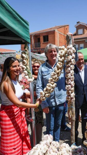 Personas en la Feria del Ajo sosteniendo ajos en Santa Marina del Rey