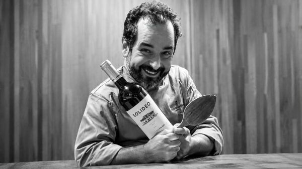 Iván Sanz Cid sosteniendo una botella de vino y una cuchara de madera