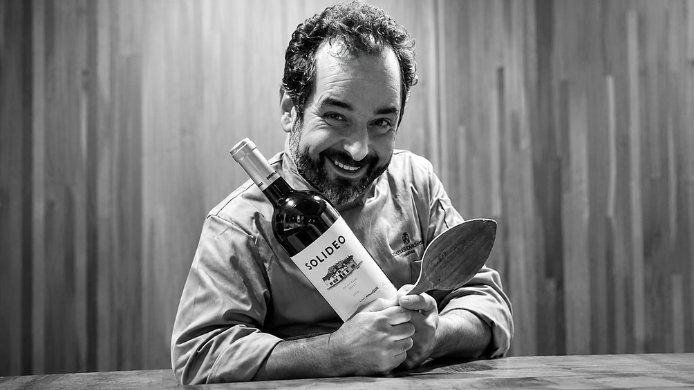 Iván Sanz Cid sosteniendo una botella de vino y una cuchara de madera