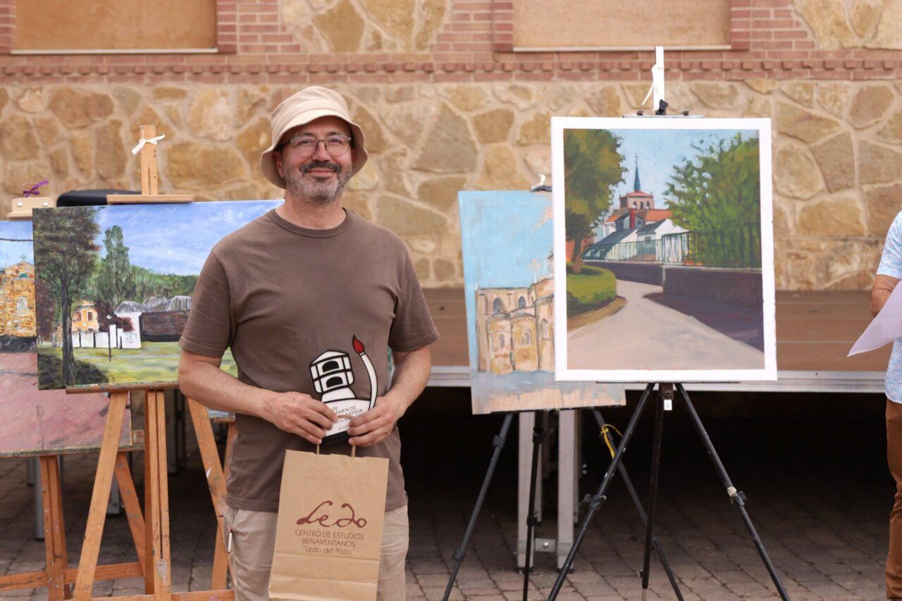 Artista sonriente con pinturas en un certamen de pintura rápida