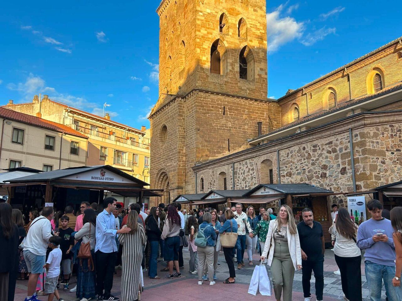 Multitud de personas en la Feria de Septiembre de Benavente con un edificio antiguo al fondo.