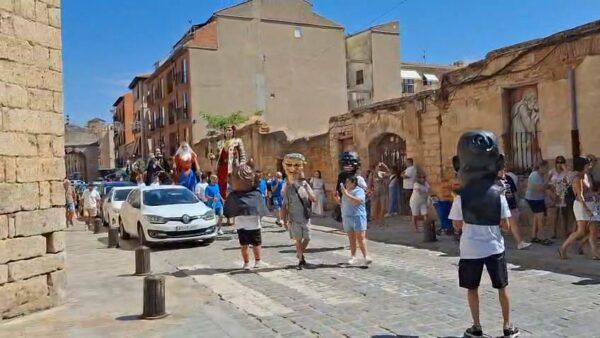 Desfile de gigantes y cabezudos en las calles de Toro con espectadores.