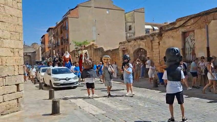 Desfile de gigantes y cabezudos en las calles de Toro con espectadores.