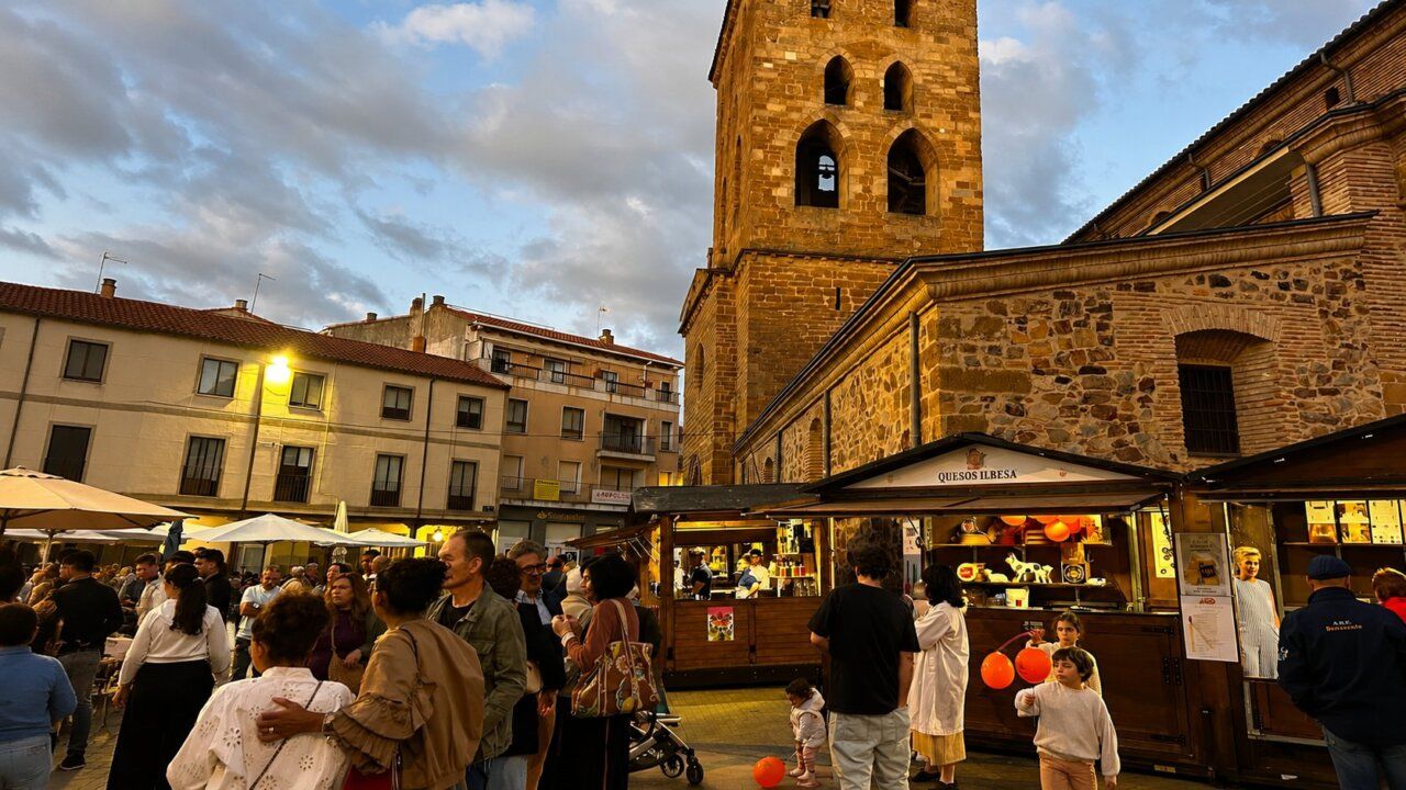 Gente disfrutando de la Feria de Septiembre en Benavente con puestos de productos locales.