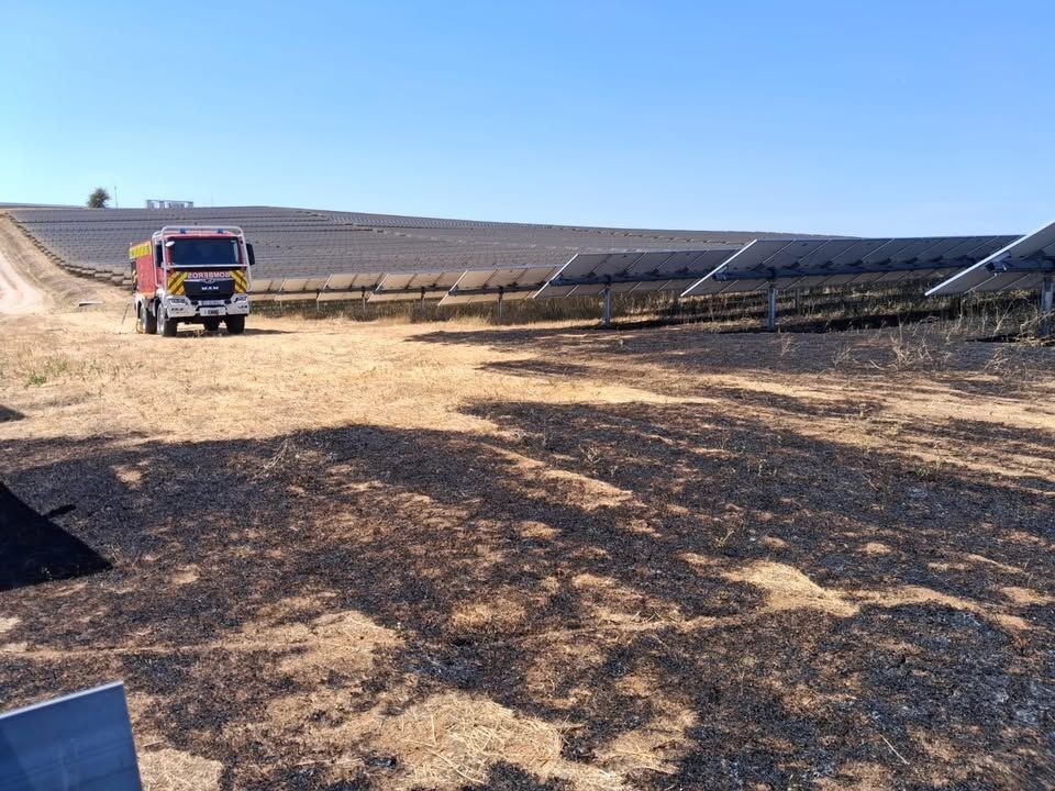 Camión de bomberos en un área afectada por incendio cerca de paneles solares.