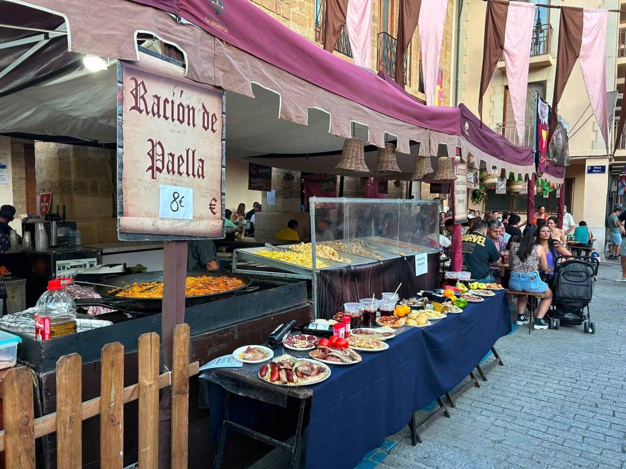 Puesto de paella en el Mercado Medieval de Benavente con gente disfrutando.