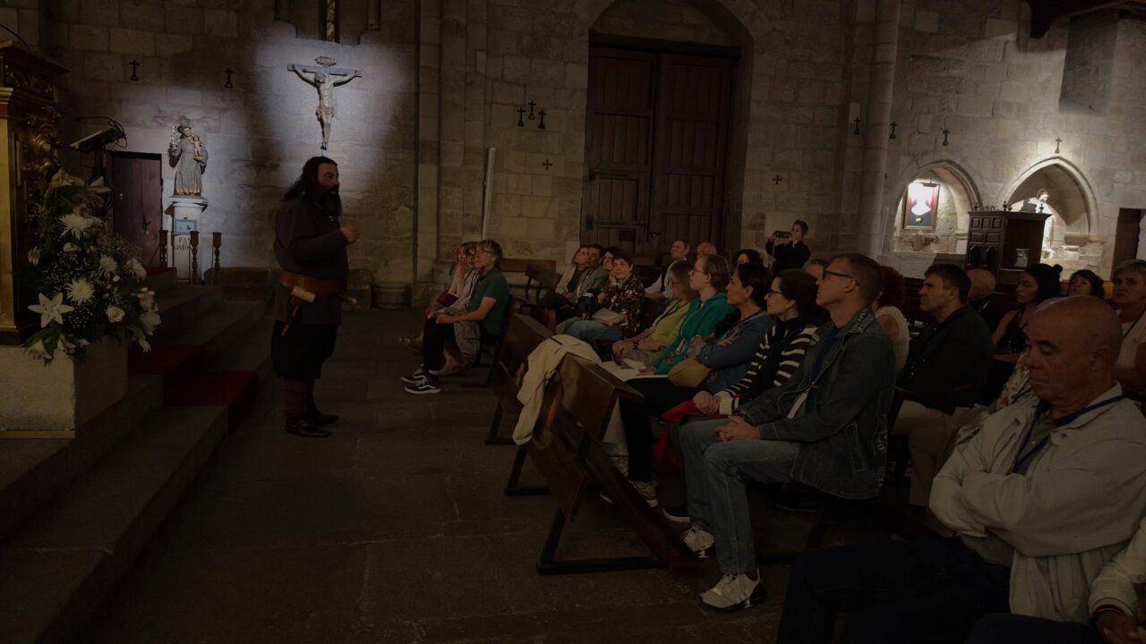 Grupo de personas escuchando a un guía en una iglesia durante la Milla Románica