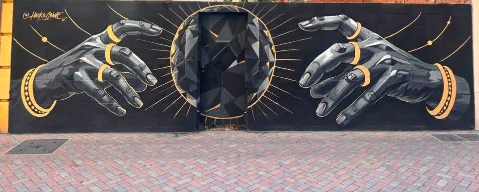 Mural artístico con manos y un eclipse solar en Benavente