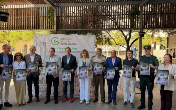 Grupo de personas sosteniendo carteles en un evento de la Asociación Española Contra el Cáncer.