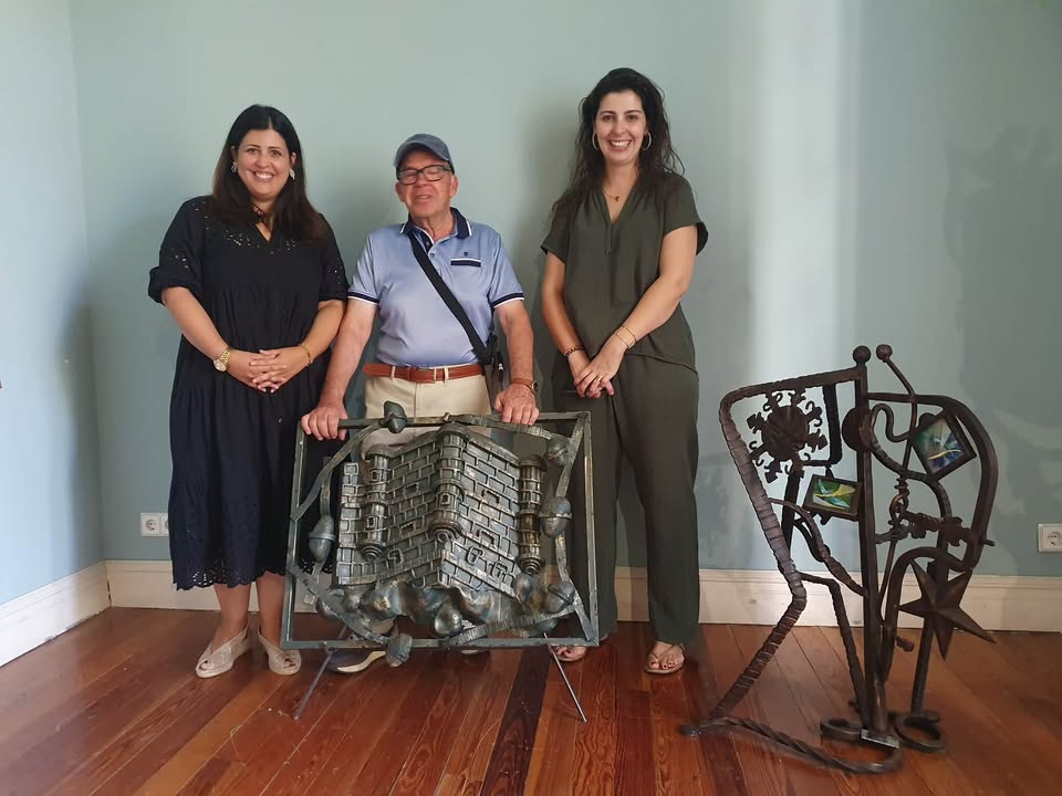 Tres personas posando junto a obras de forja en una exposición