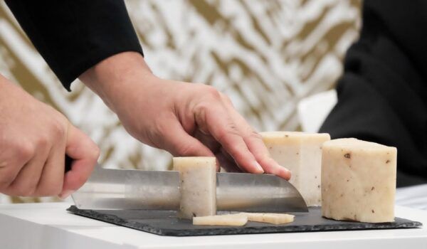 Persona cortando queso en una mesa durante evento comercial