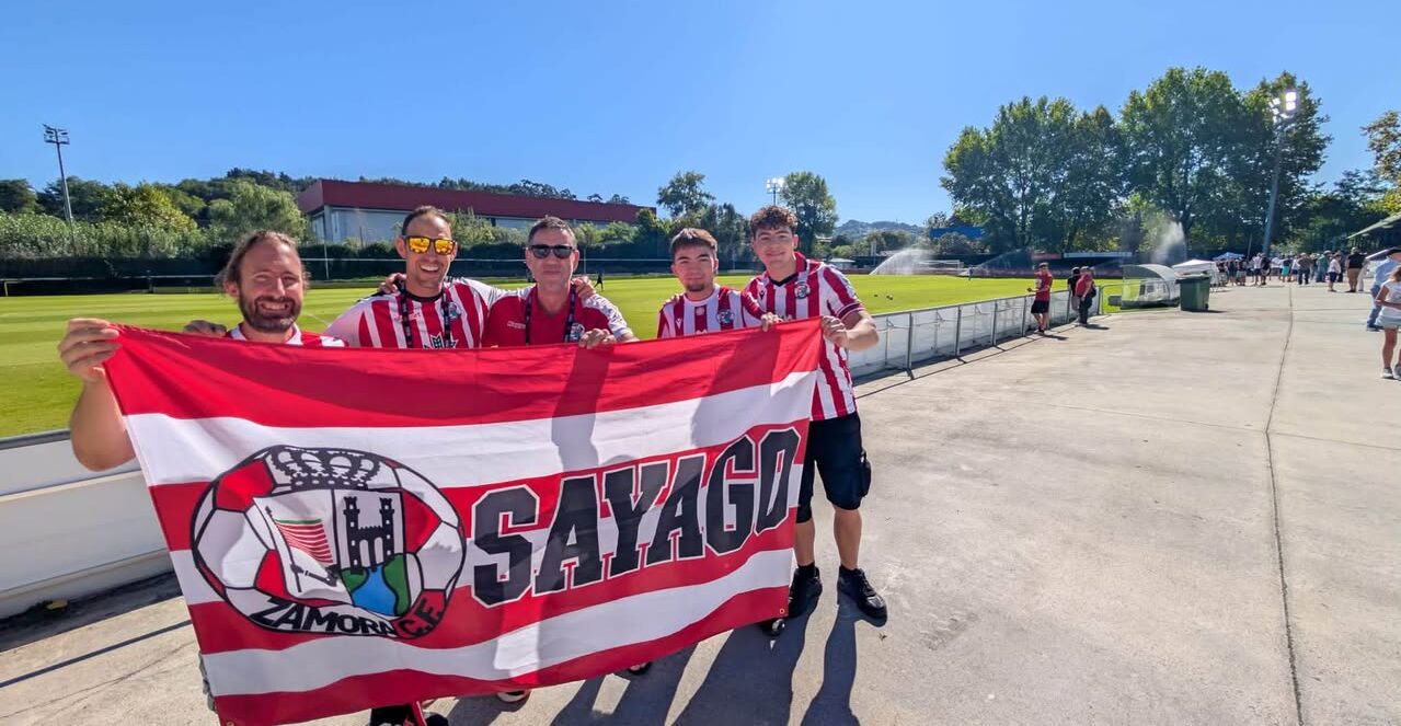 Aficionados del Zamora CF sosteniendo una bandera en un campo de fútbol