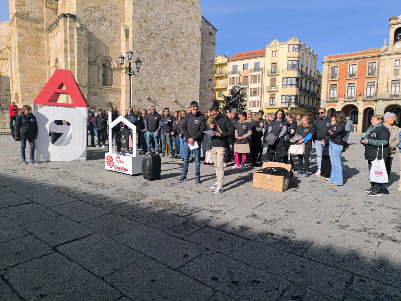 Personas reunidas junto a un expositor de Cáritas sobre sinhogarismo en una plaza