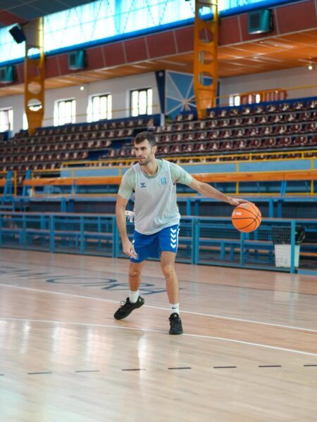 Un jugador controla un balón de baloncesto en una pista cubierta.