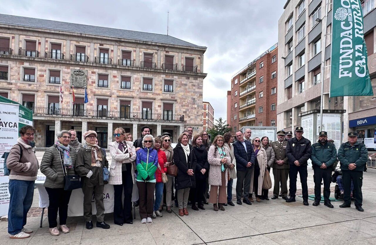 Grupo de personas posa junto a puestos de AZAYCA en una plaza urbana.