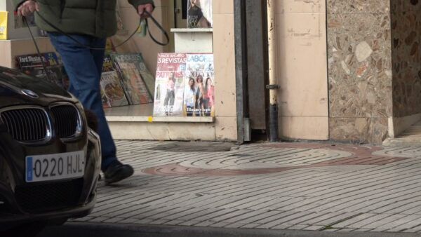 Persona paseando un perro frente a una tienda en Benavente