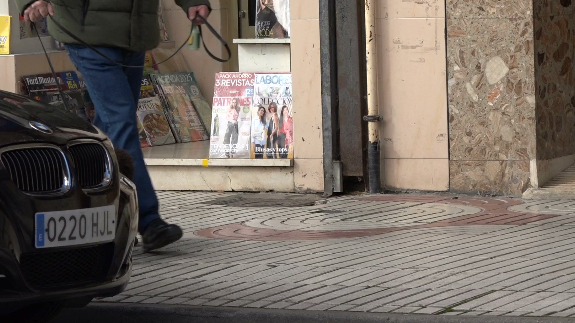 Persona paseando un perro frente a una tienda en Benavente