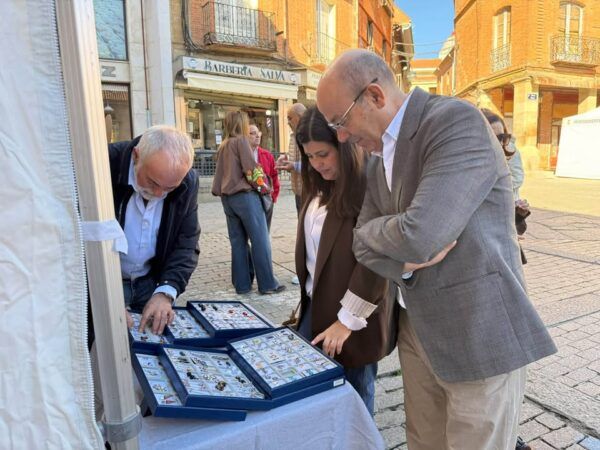 Inauguración de la Feria del Pequeño Comercio en Benavente con asistentes observando productos