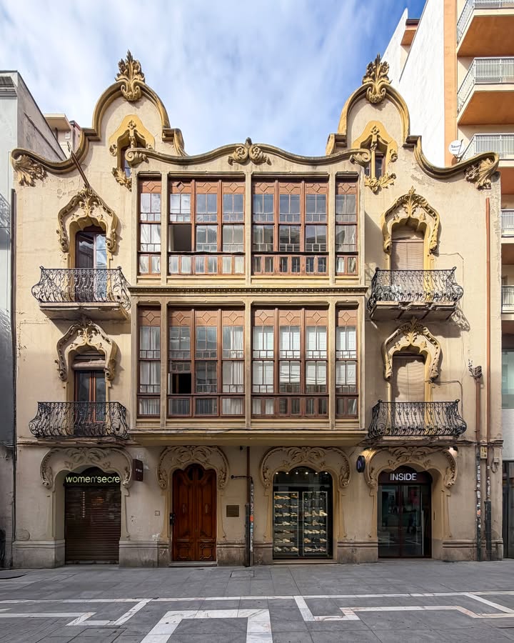 Fachada ornamentada de dos casas modernistas con balcones de hierro y grandes ventanales