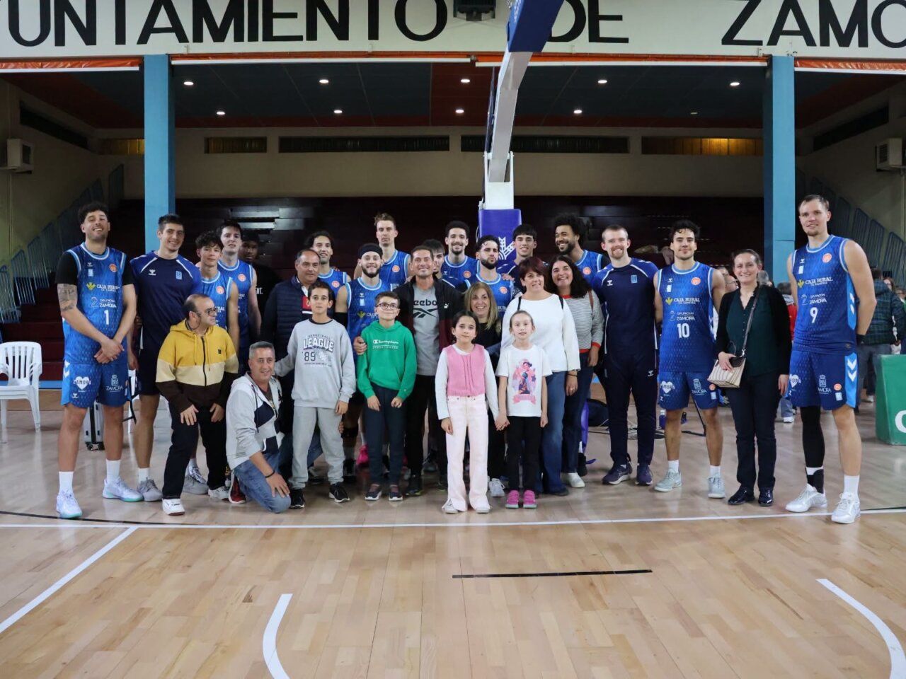 Jugadores del CB Zamora posan con varias personas en una pista de baloncesto.