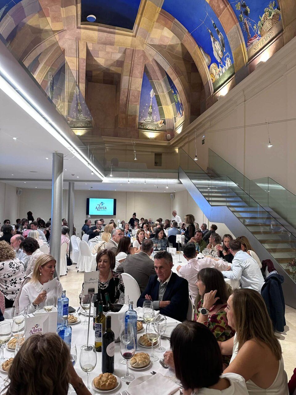 Asistentes comparten una cena de AZAYCA en un salón con mesas dispuestas.