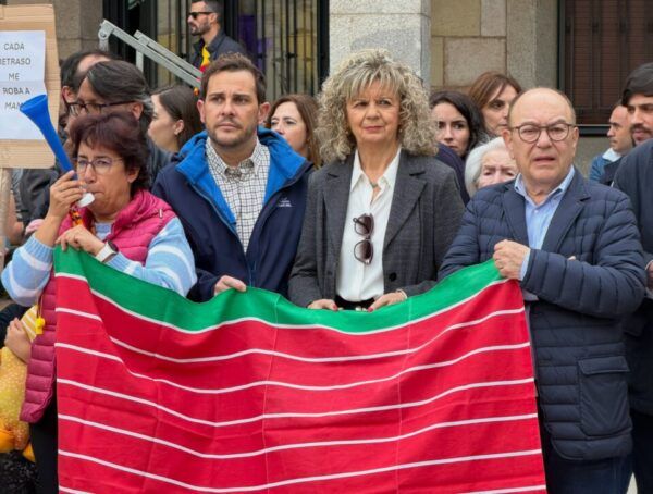 Grupo de personas sostiene una pancarta durante una concentración ciudadana frente a un edificio.