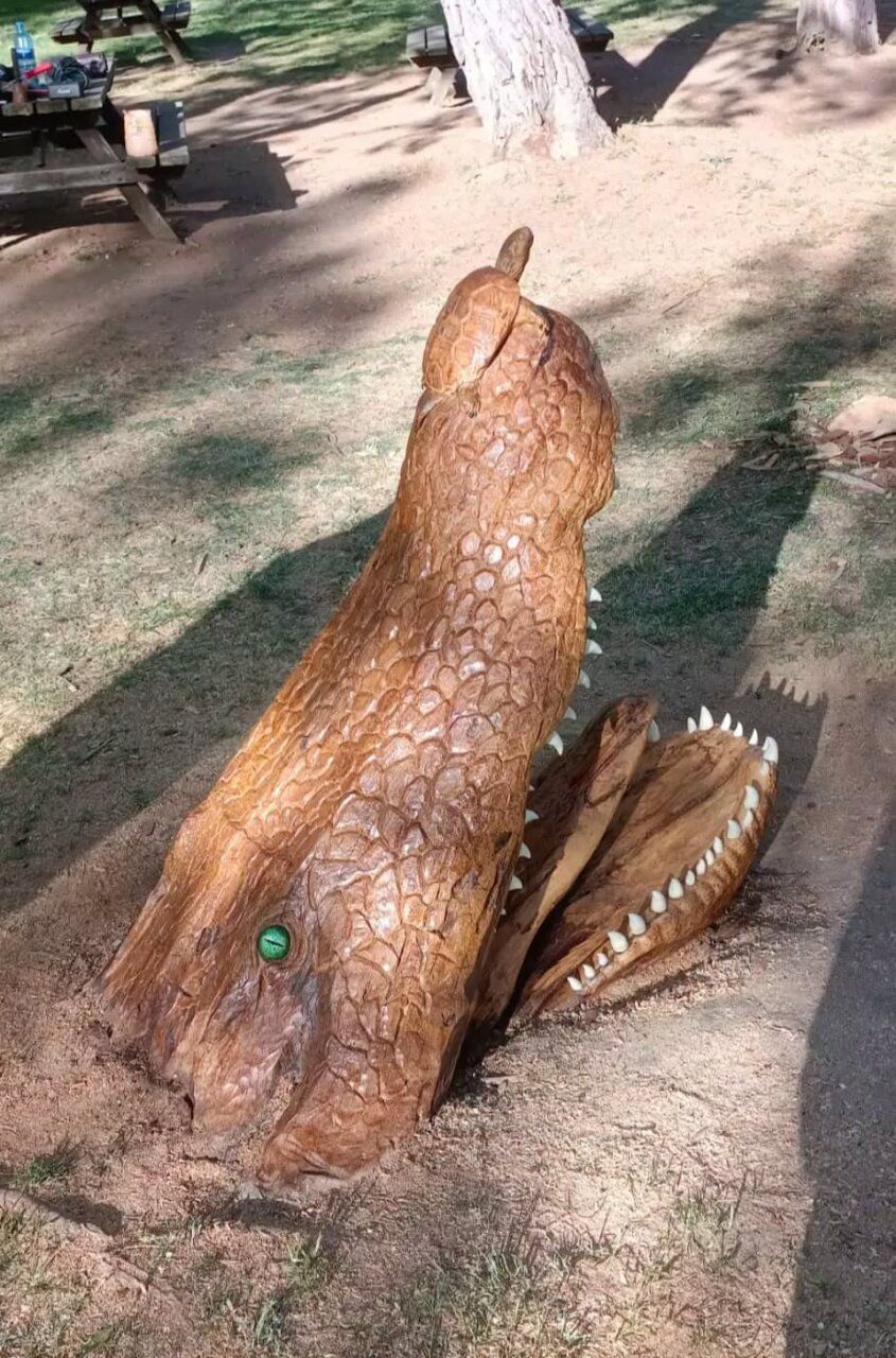 Escultura de un cocodrilo con una tortuga sobre el lomo en un parque.
