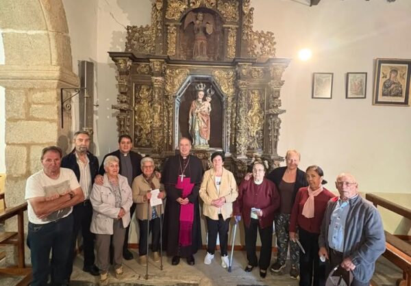 Grupo de personas posa frente a un retablo ornamentado en el interior de una iglesia.