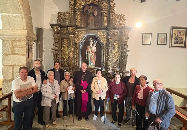 Grupo de personas posa frente a un retablo ornamentado en el interior de una iglesia.