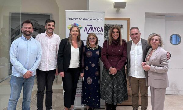 Siete personas posan junto a un cartel de apoyo al paciente de AZAYCA.