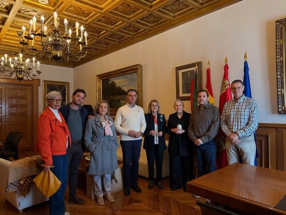 Grupo de ocho personas posa en una sala con techo de madera y varias banderas.
