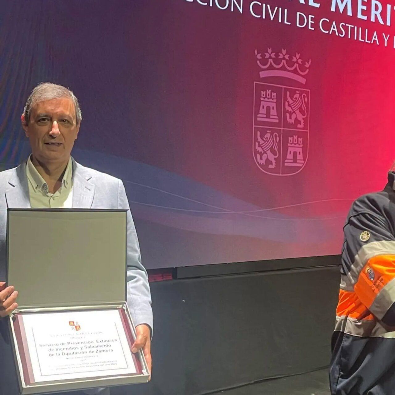 Hombre sostiene una placa de reconocimiento ante un fondo de Protección Civil de Castilla y León