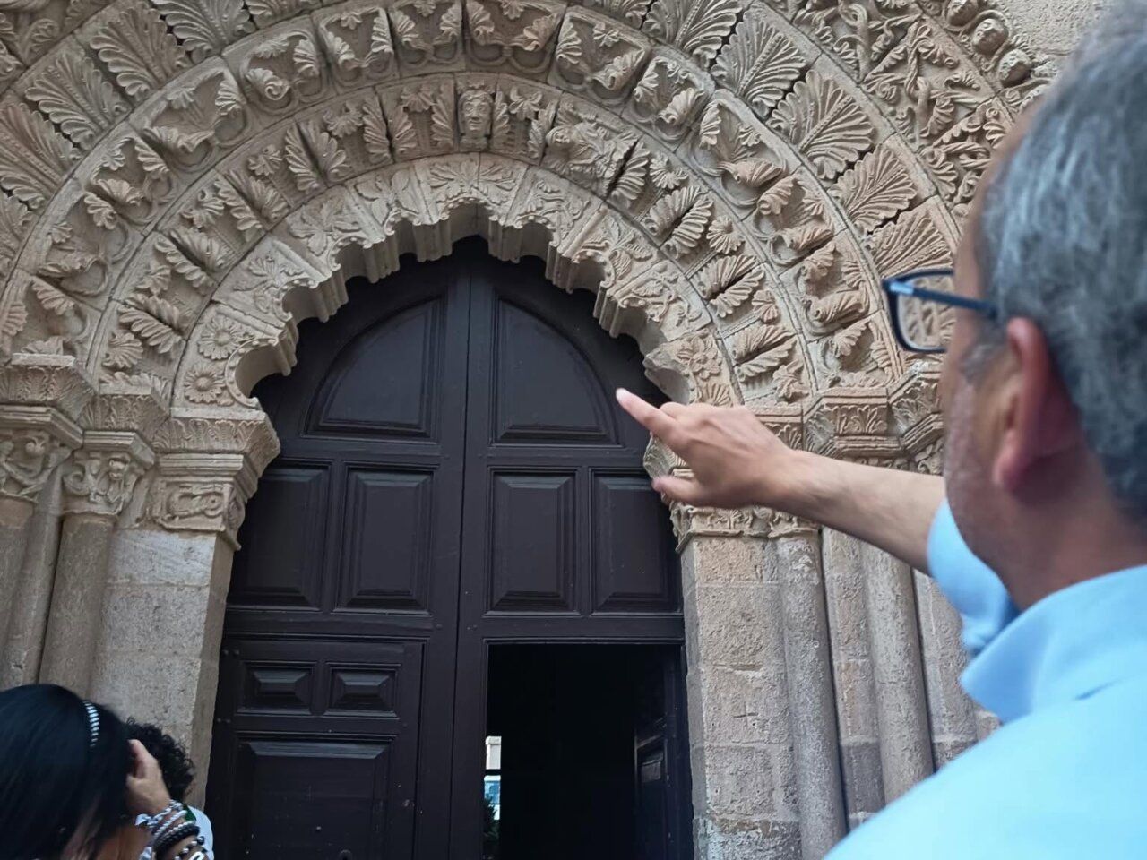 Portada de piedra tallada de La Magdalena de Zamora y una persona señalándola