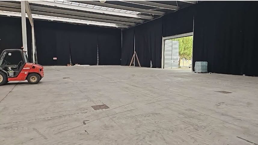 Interior de un pabellón ferial con suelo de hormigón y una carretilla elevadora.