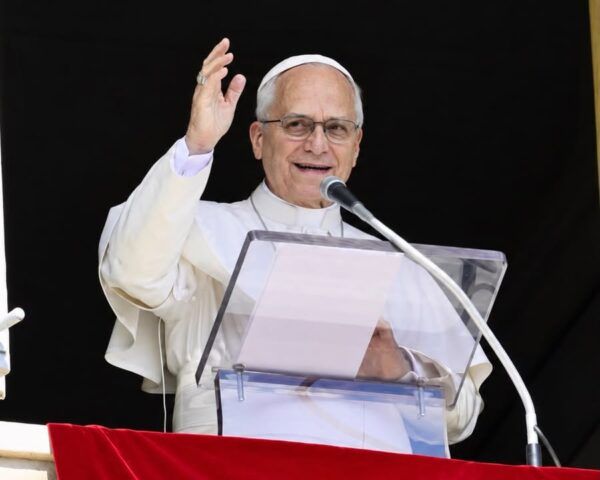El papa León XIV saluda mientras habla en un podio