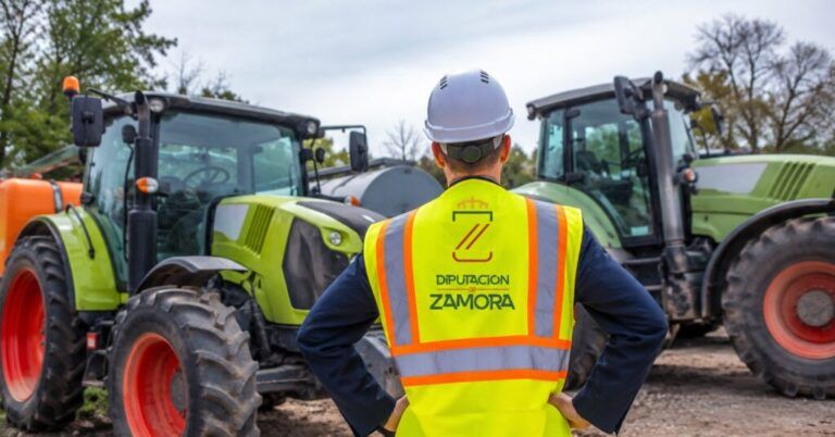 Persona con casco y chaleco reflectante frente a varios tractores agrícolas
