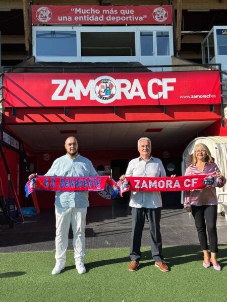 Tres personas sostienen bufandas del CD Benavente y Zamora CF frente a un rótulo del club.